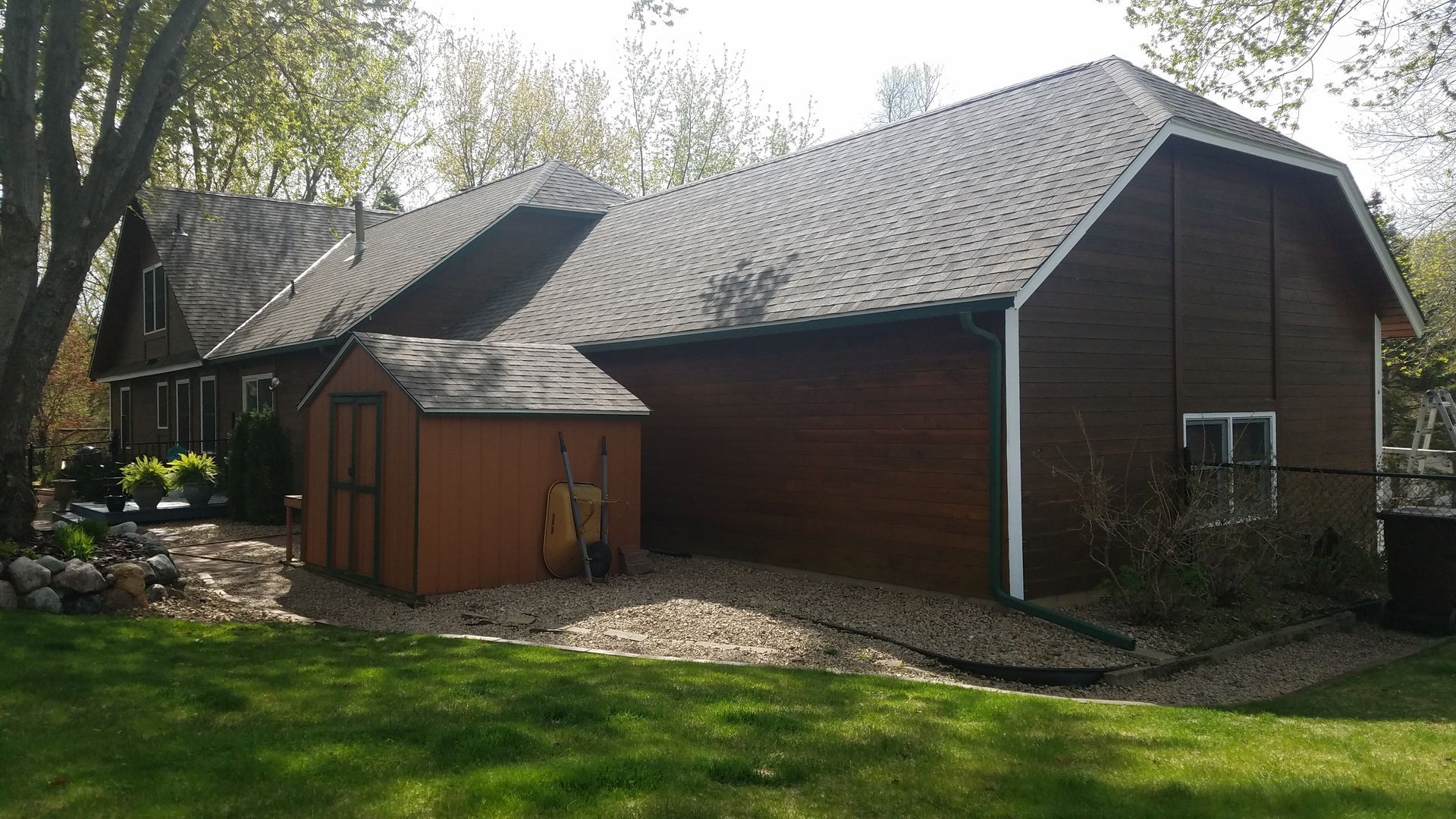 A large brown house with a shed in front of it.