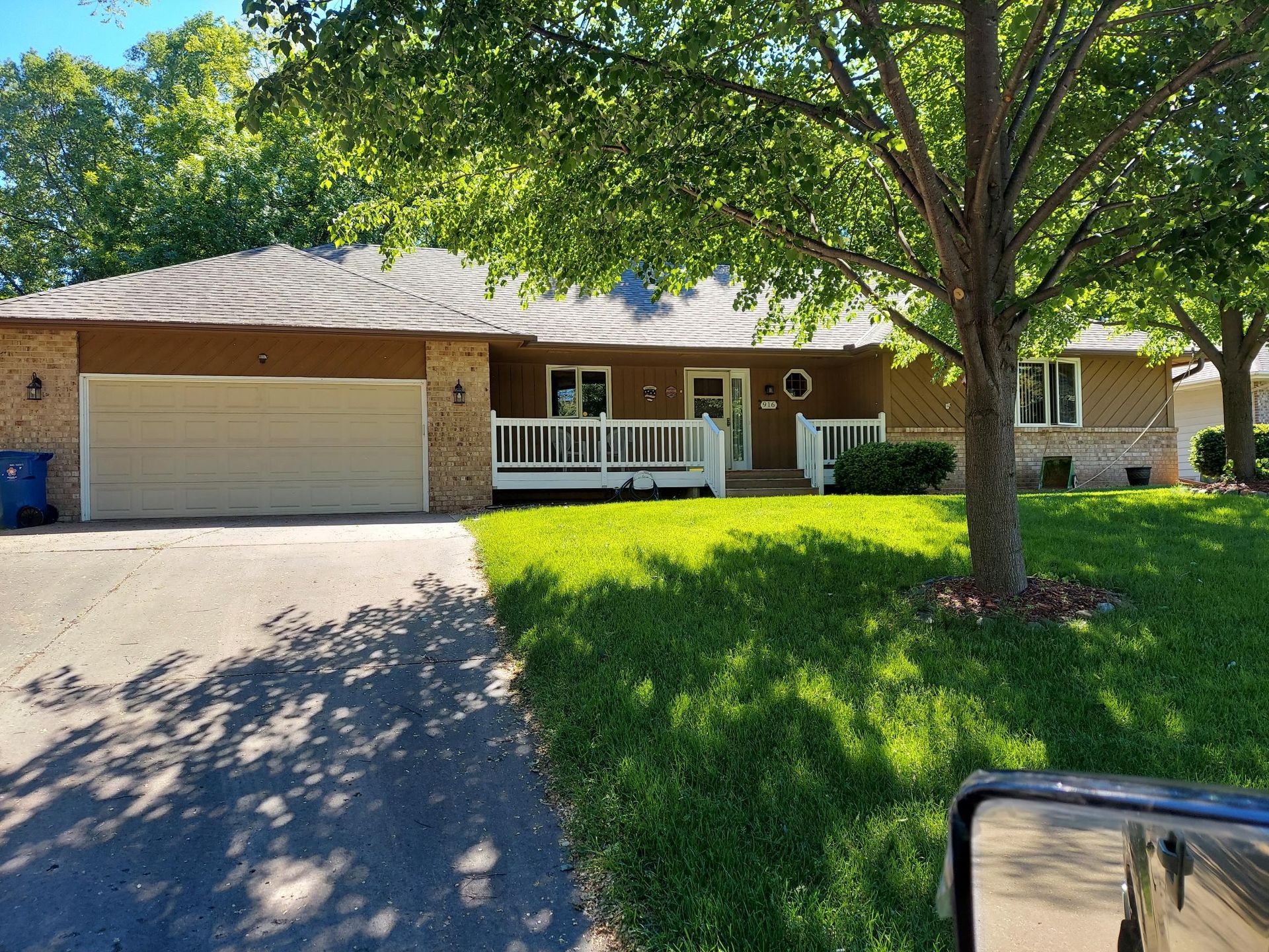 A car is parked in front of a house with a large garage.