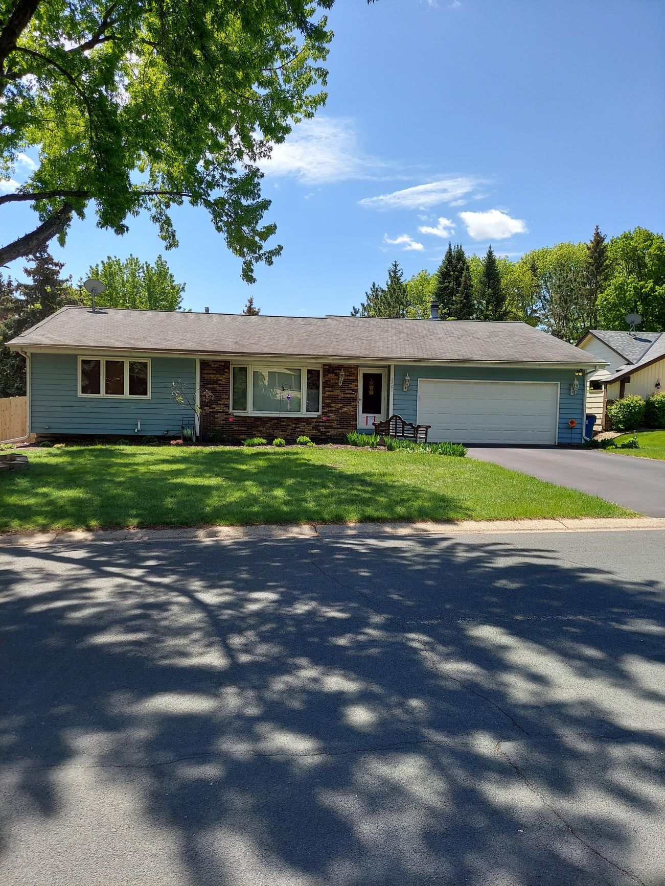 A blue house with a gray roof and a white garage door