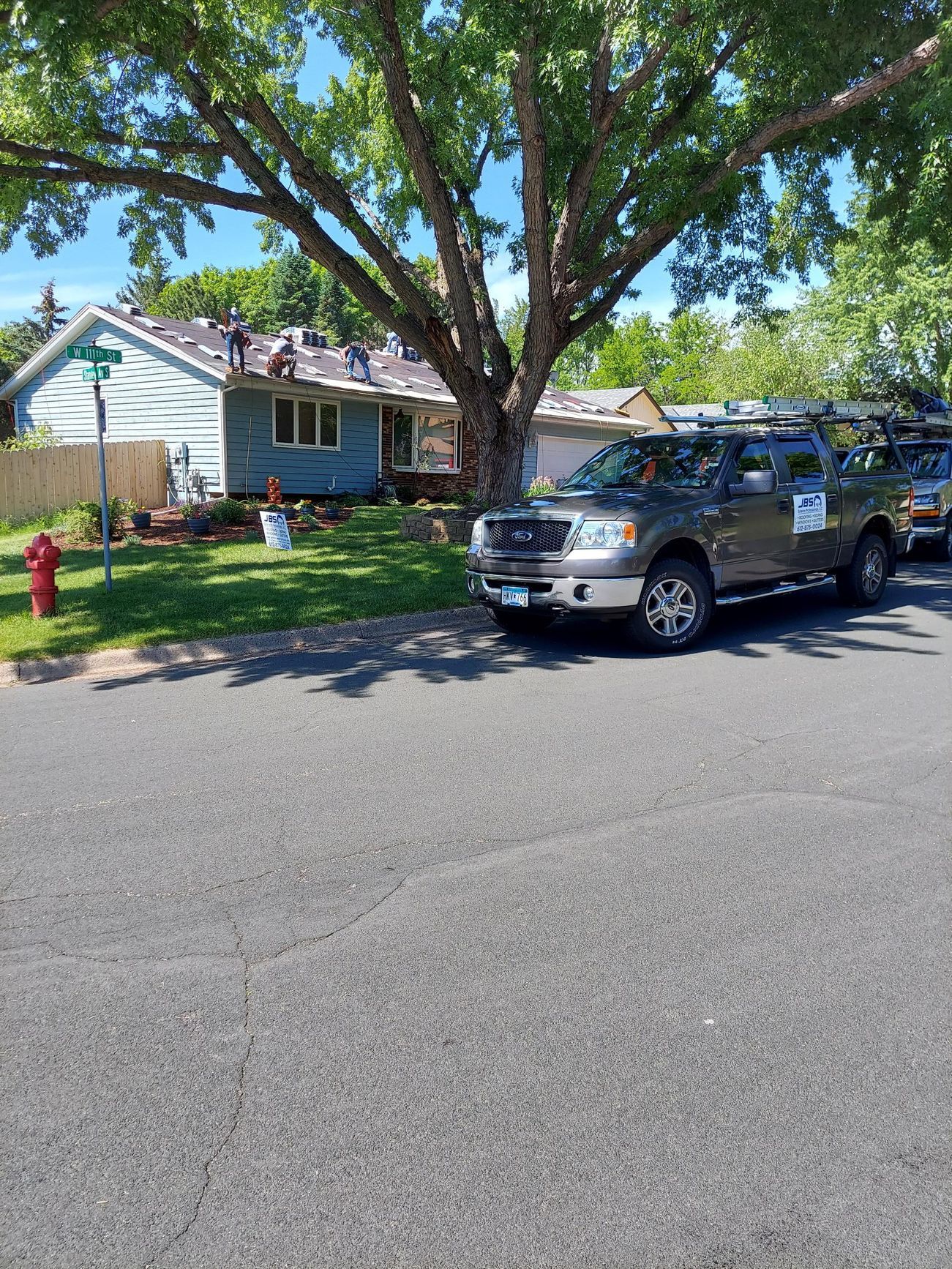 Two trucks are parked on the side of the road in front of a house.