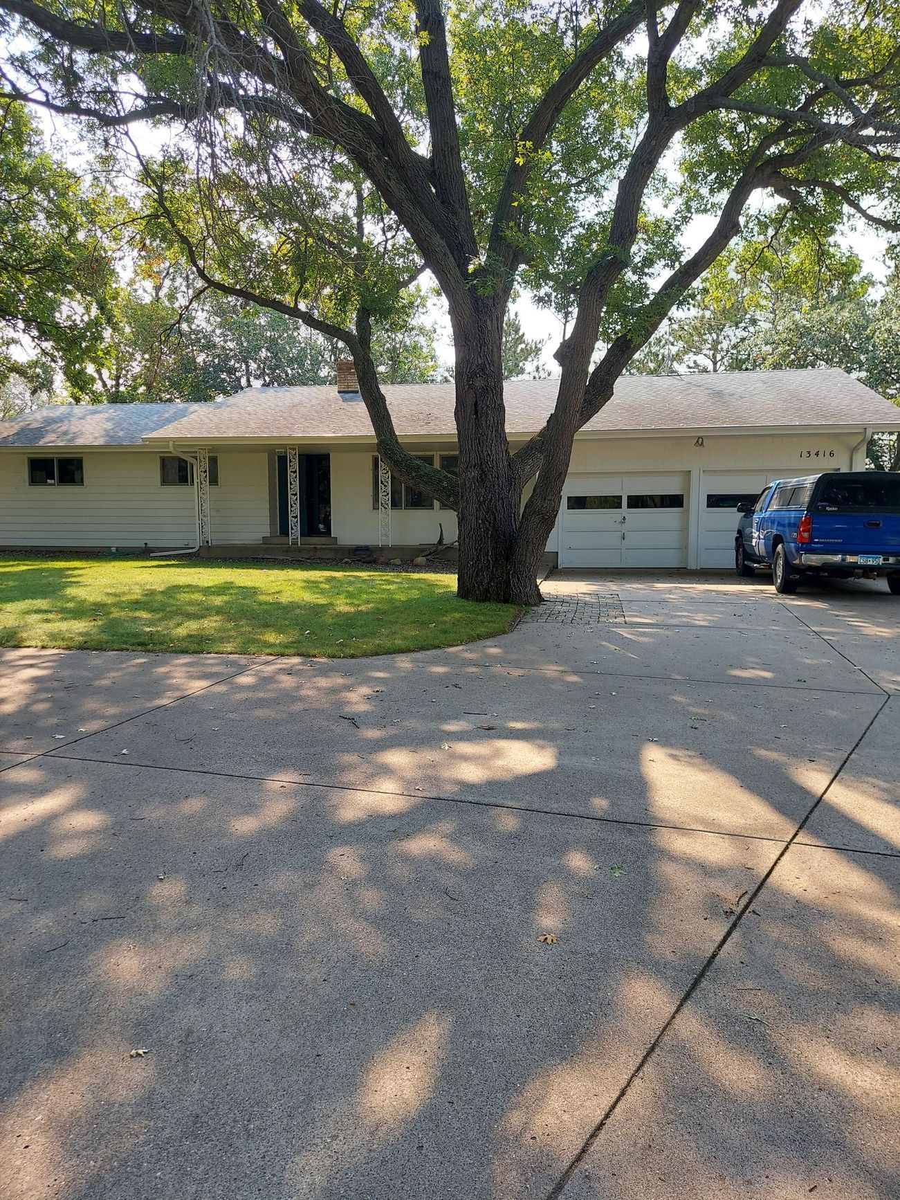 A white house with a blue truck parked in front of it.