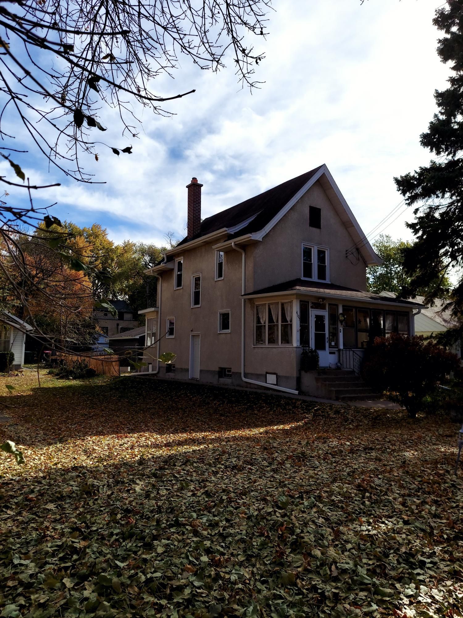 A house with a porch and a lot of leaves on the ground