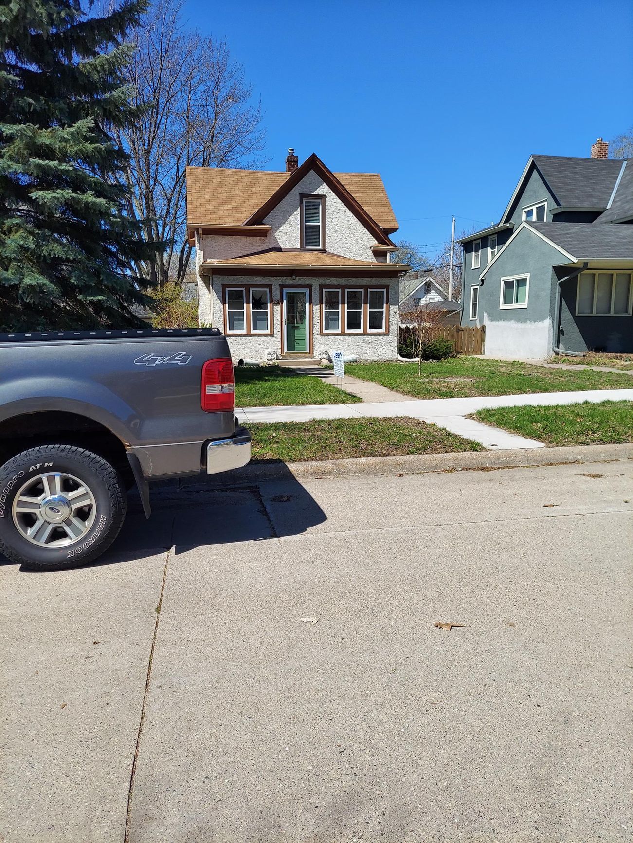 A truck is parked in front of a house on a sunny day.