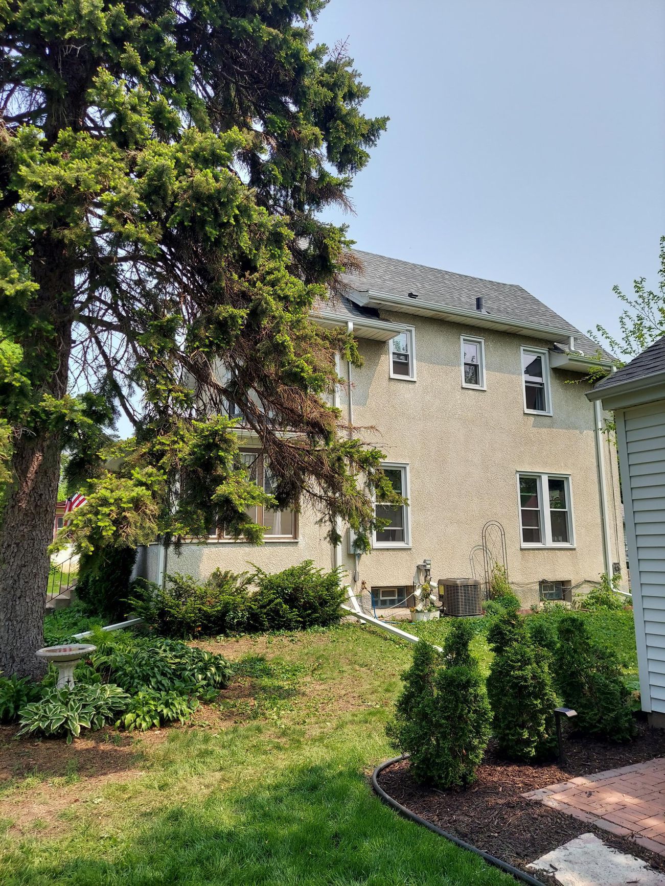 A large house with a lot of windows is surrounded by trees and bushes.