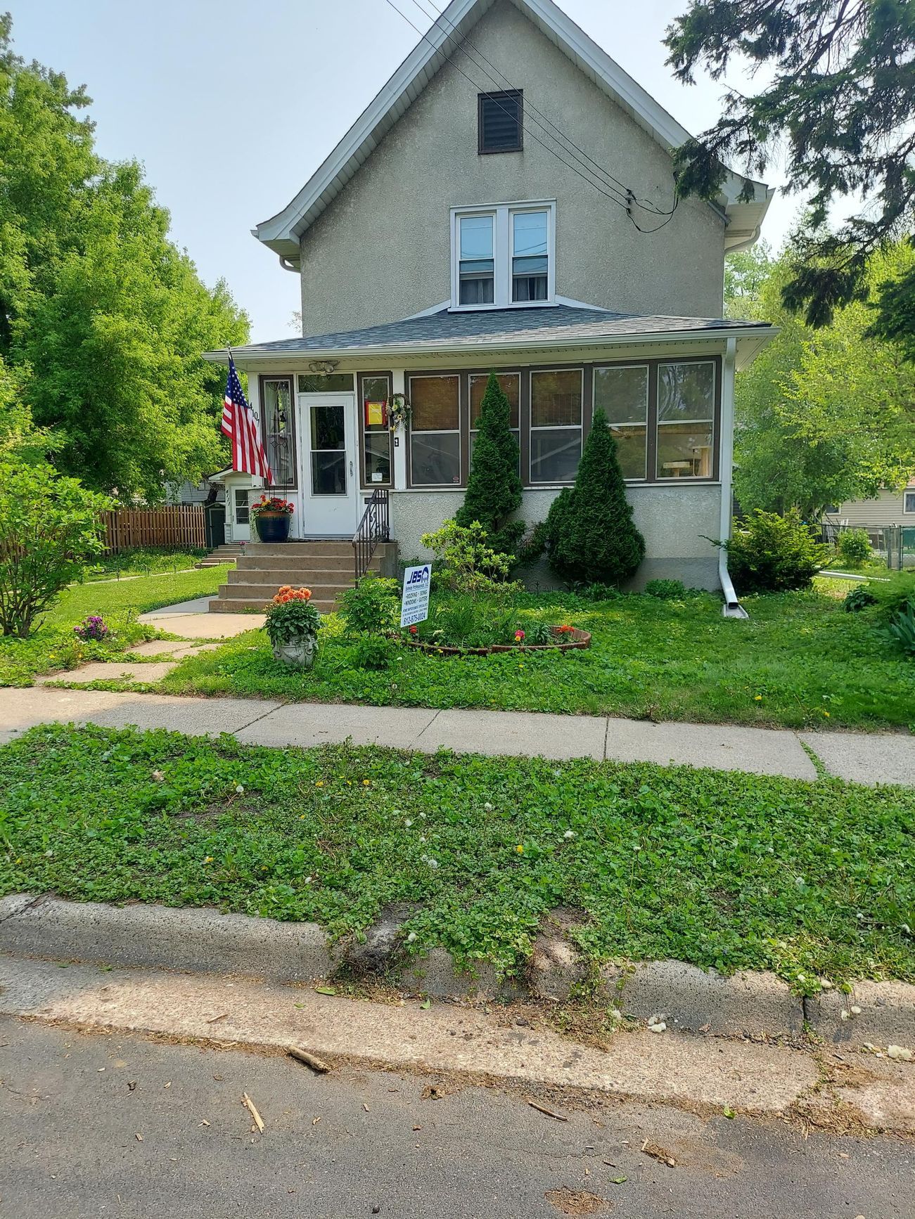 A large house with a roof that is covered in shingles is sitting on top of a lush green lawn.