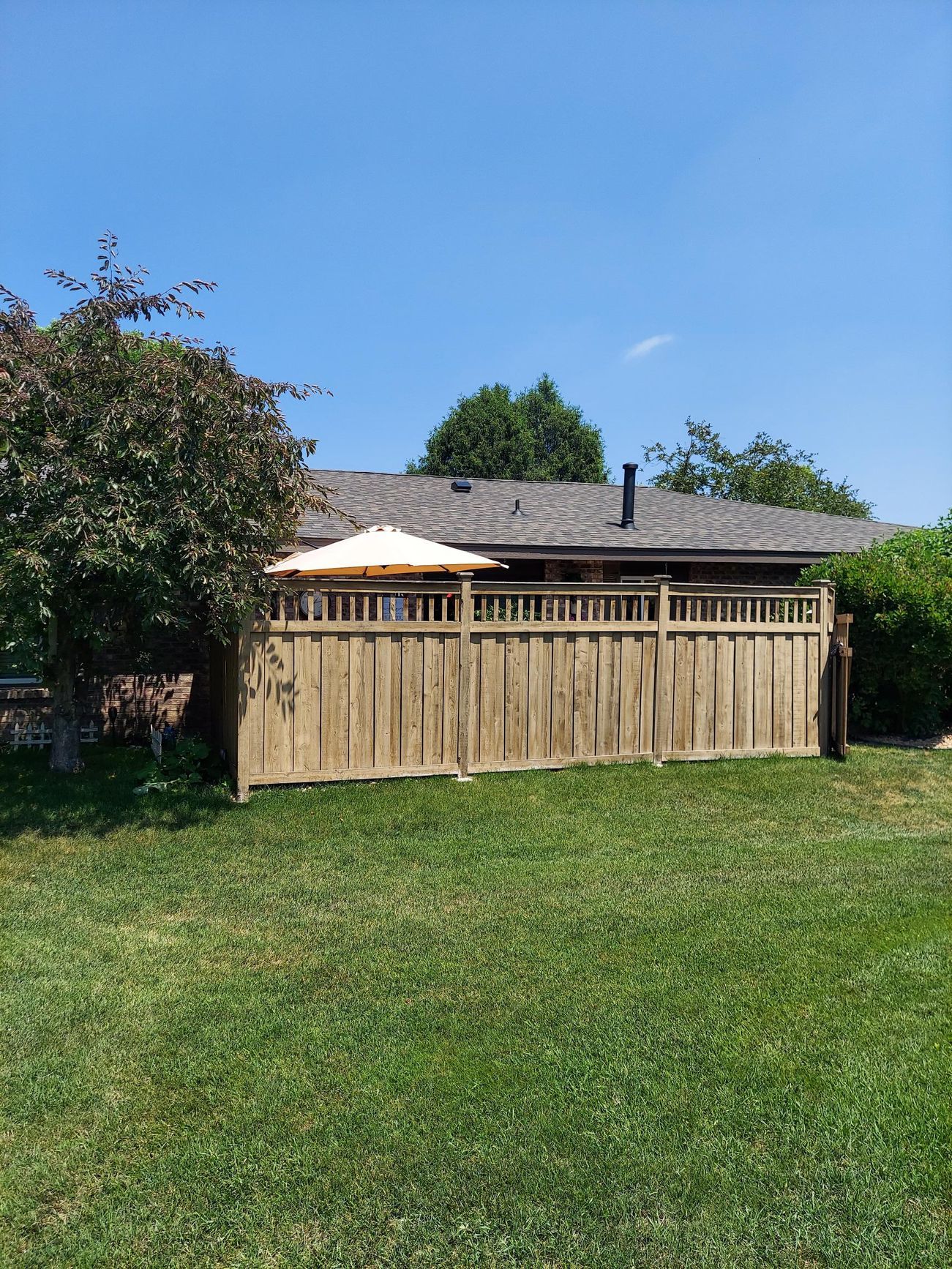 There is a wooden fence in the backyard of a house.