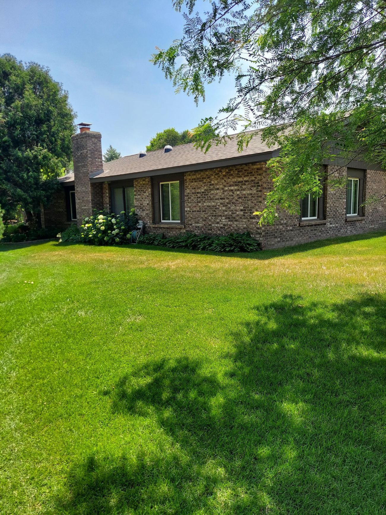 A brick house with a large lawn in front of it.