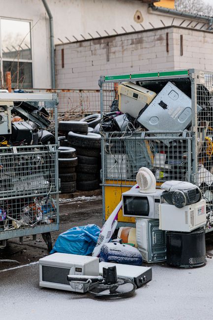 Electronic waste recycling yard with dumpsters, and old appliances showcasing white goods drop-off.