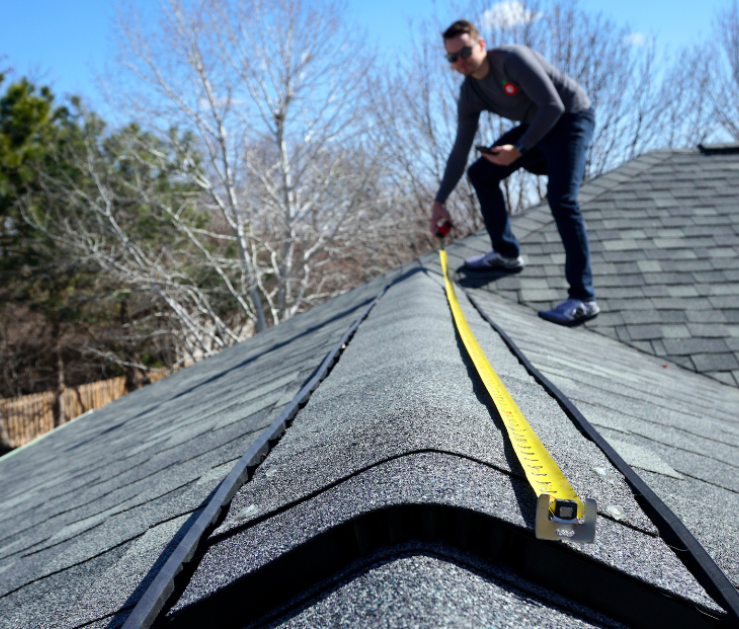 A man is measuring a roof with a tape measure