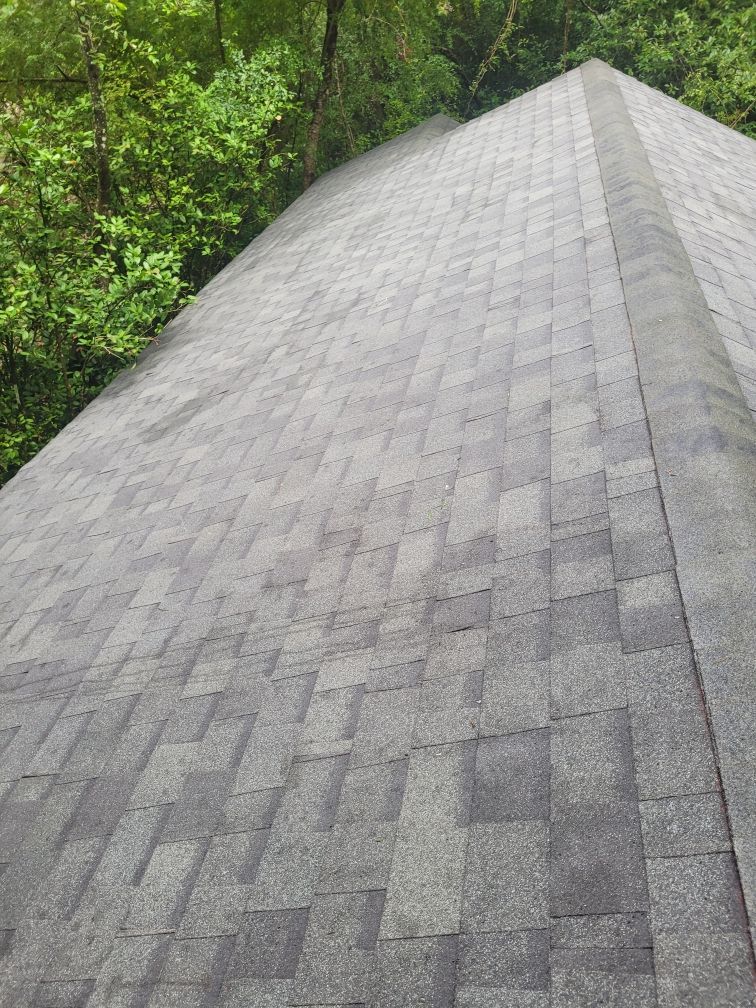 A roof with a lot of shingles on it is surrounded by trees.