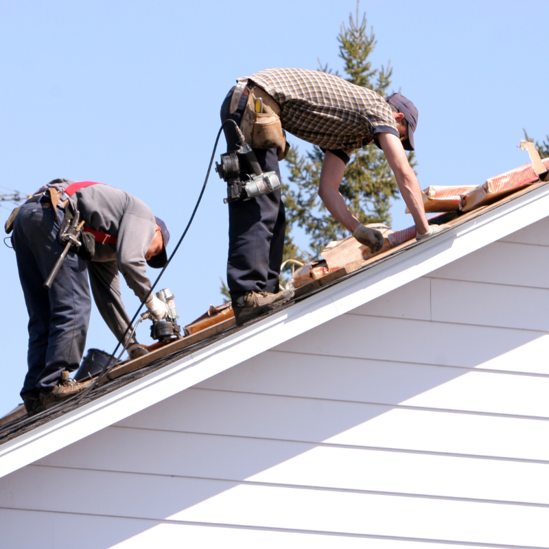 Two men are working on the roof of a house