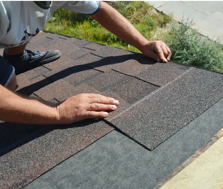 A man is laying shingles on a roof.