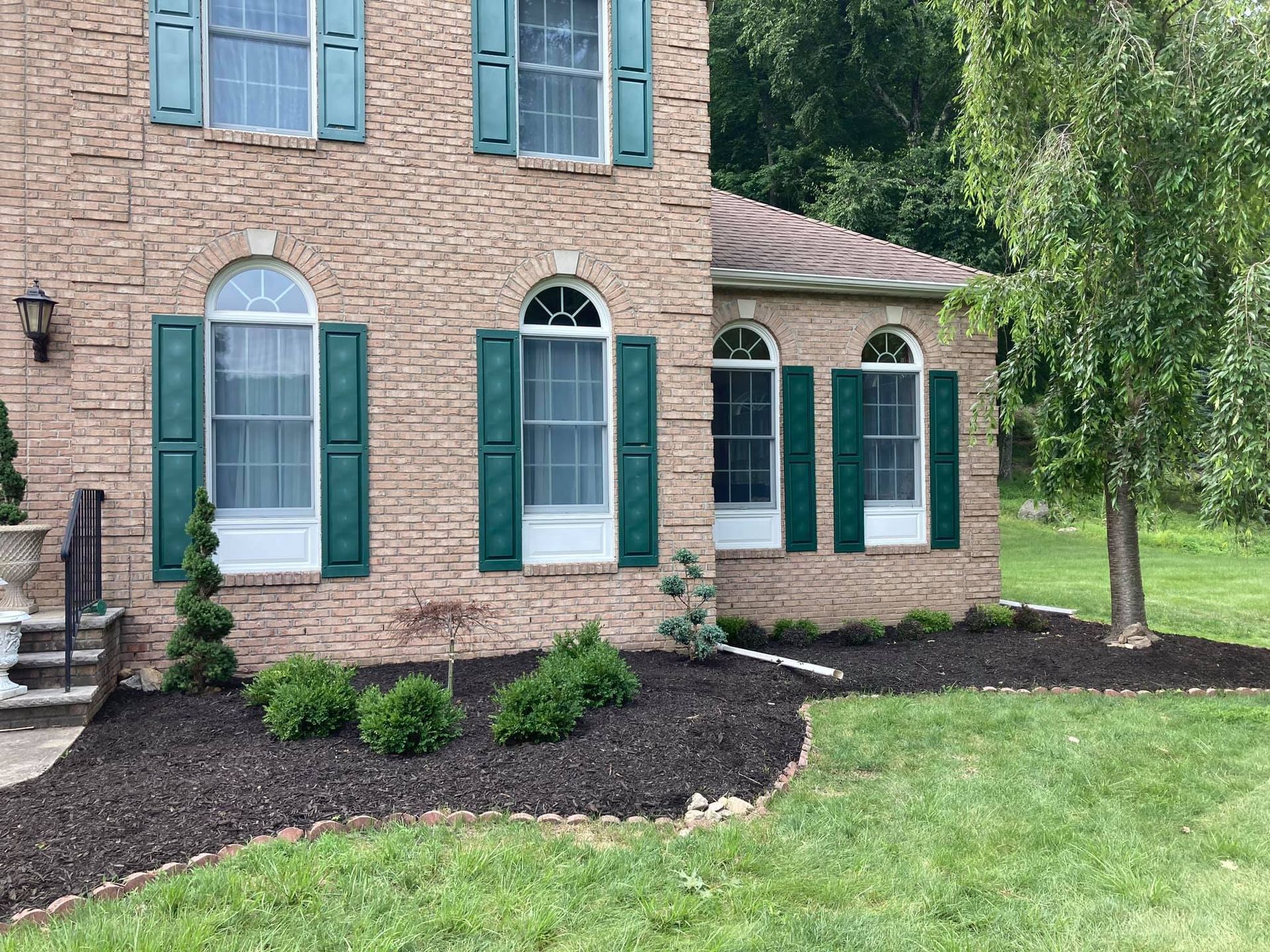 Front side of a house that had landscaping completed with fresh mulch laid out, grass cut and plants trimmed.