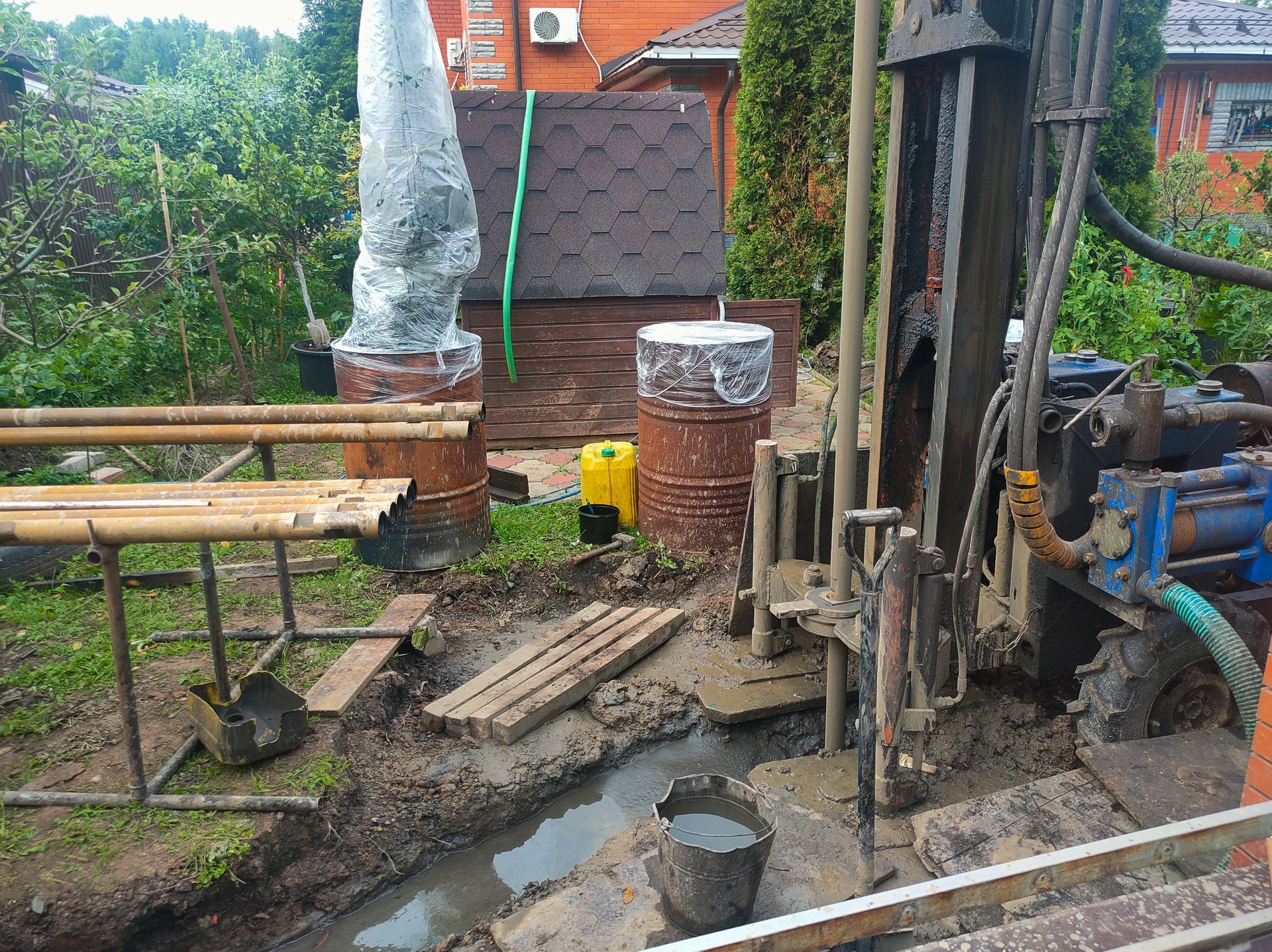 A drilling rig digs a mud trench, building a domestic water well.