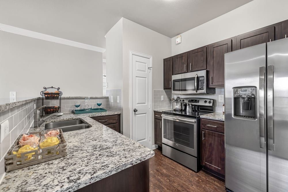 A kitchen with stainless steel appliances and granite counter tops at Marquis at Silver Oaks in Grapevine, TX.