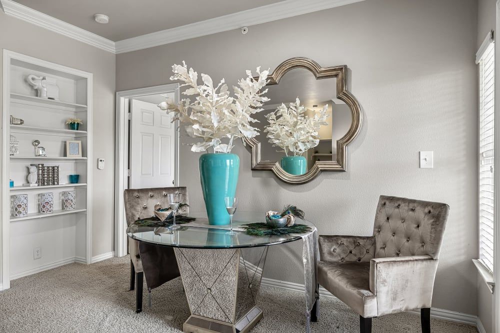 Apartment dining room with a table and chairs and a mirror on the wall at Marquis at Silver Oaks in Grapevine, TX.