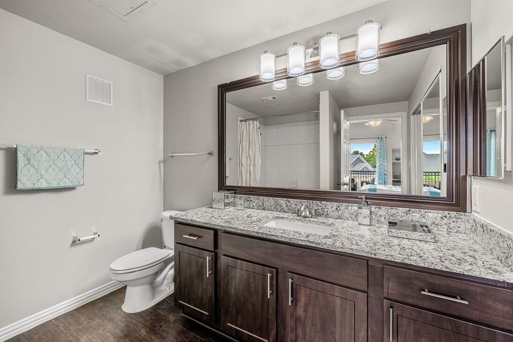 Apartment bathroom with a toilet, sink and mirror at Marquis at Silver Oaks in Grapevine, TX.