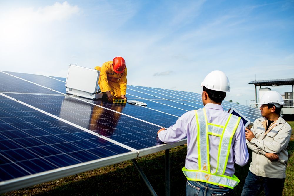 Two Men Are Working On A Solar Panel In A Field — Trusted Energy Solutions In Surfers Paradise, QLD