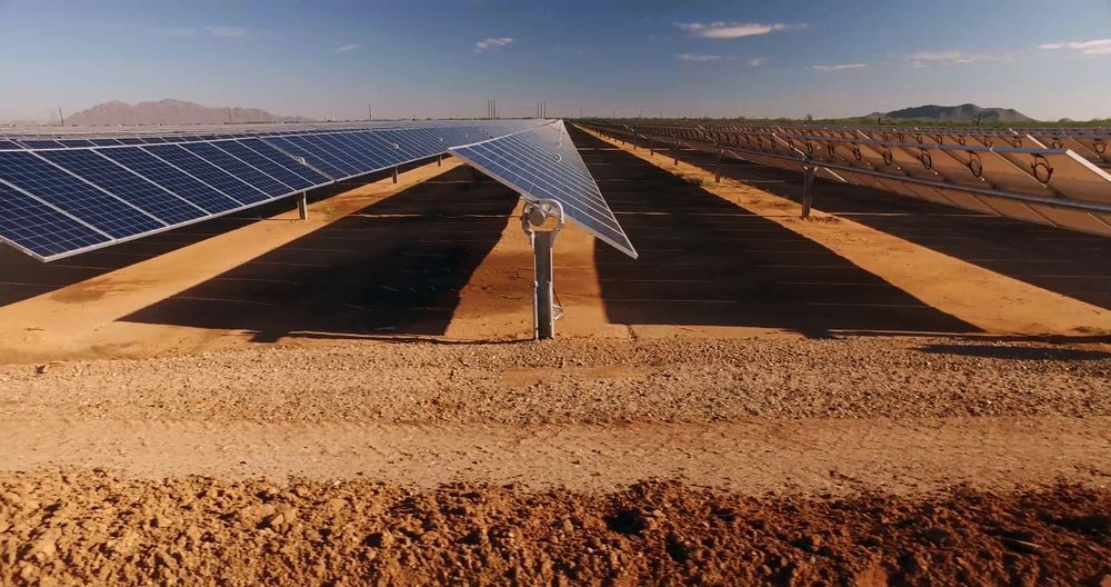 A Row Of Solar Panels Are Sitting On Top Of A Dirt Field — Trusted Energy Solutions In Wilston, QLD