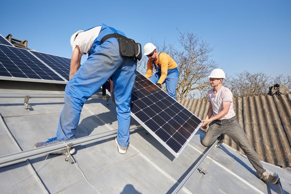Three Men Are Installing Solar Panels On A Roof — Trusted Energy Solutions In Everton Hills, QLD