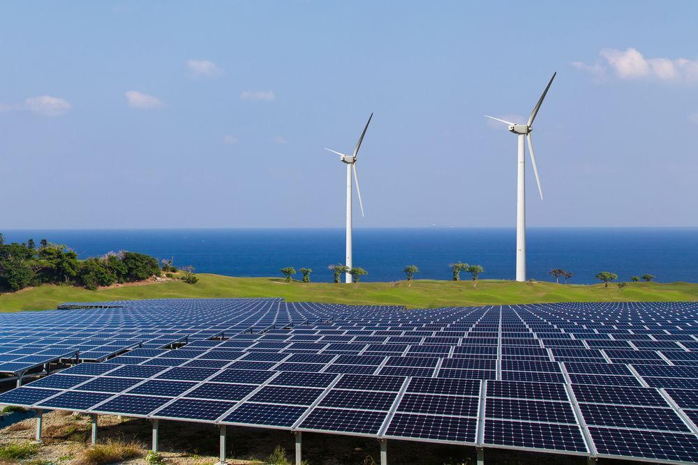 A Field Of Solar Panels And Wind Turbines With The Ocean In The Background — Trusted Energy Solutions In Everton Hills, QLD