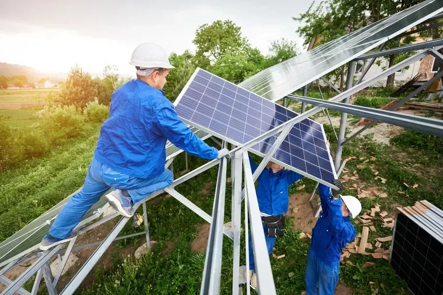A Group Of Men Are Installing Solar Panels On A Roof — Trusted Energy Solutions In Everton Hills, QLD