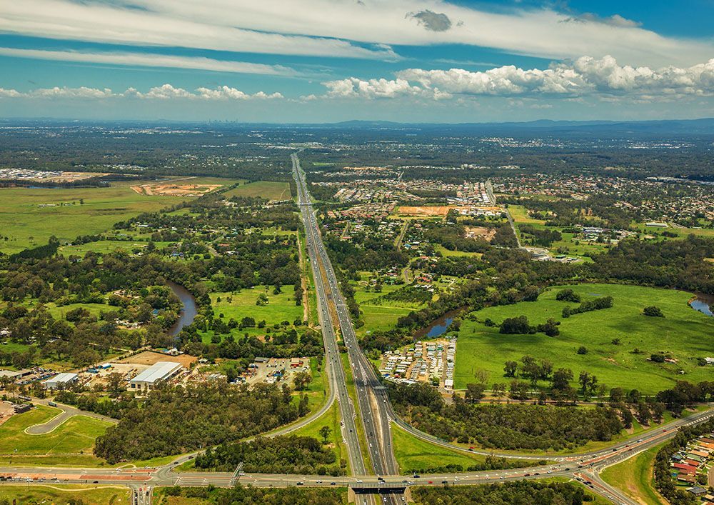 An Aerial View Of A Highway Going Through A Lush Green Field — Trusted Energy Solutions In Helensvale, QLD