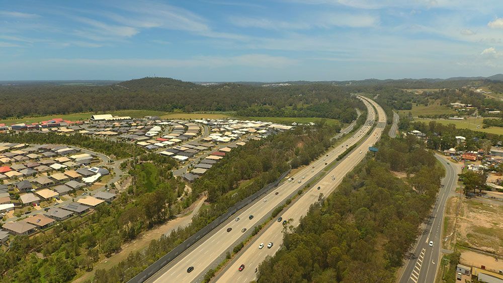 An Aerial View Of A Highway Surrounded By Trees And Houses — Trusted Energy Solutions In Runcorn, QLD