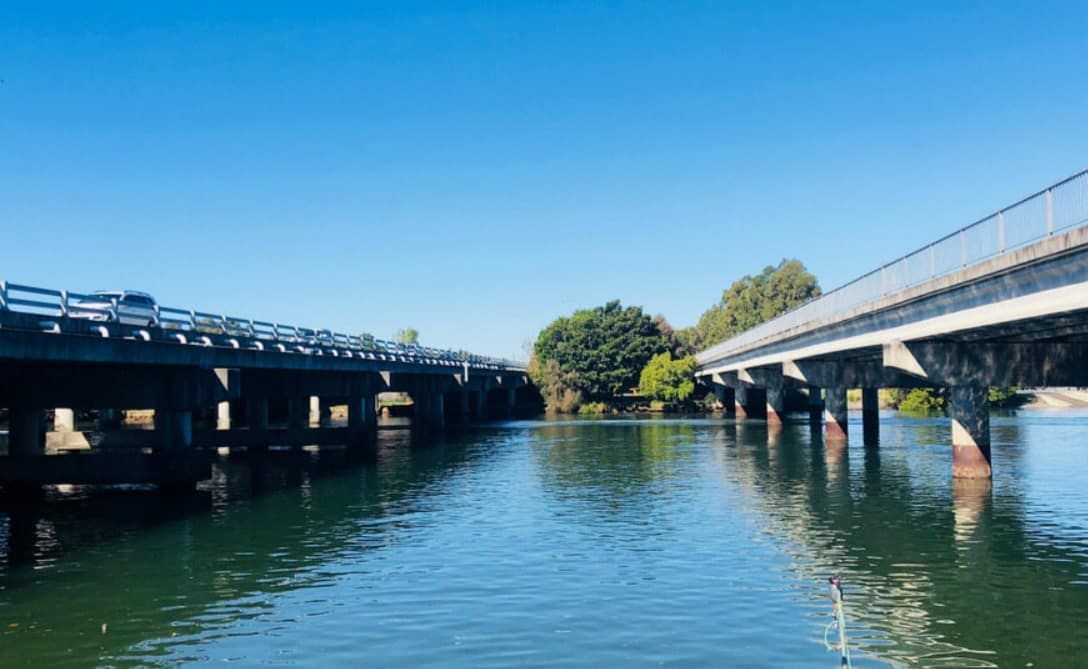 A Bridge Over a Body of Water With a Blue Sky in the Background — Trusted Energy Solutions In Coomera, QLD