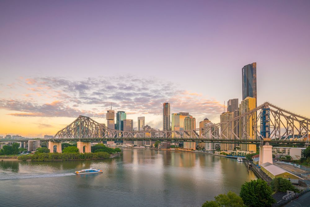 A Bridge Over A River With A City Skyline In The Background — Trusted Energy Solutions In Sanctuary Cove, QLD