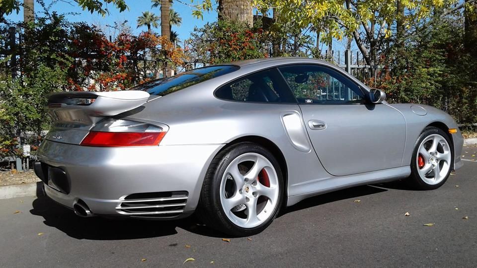 A silver porsche turbo is parked on the side of the road