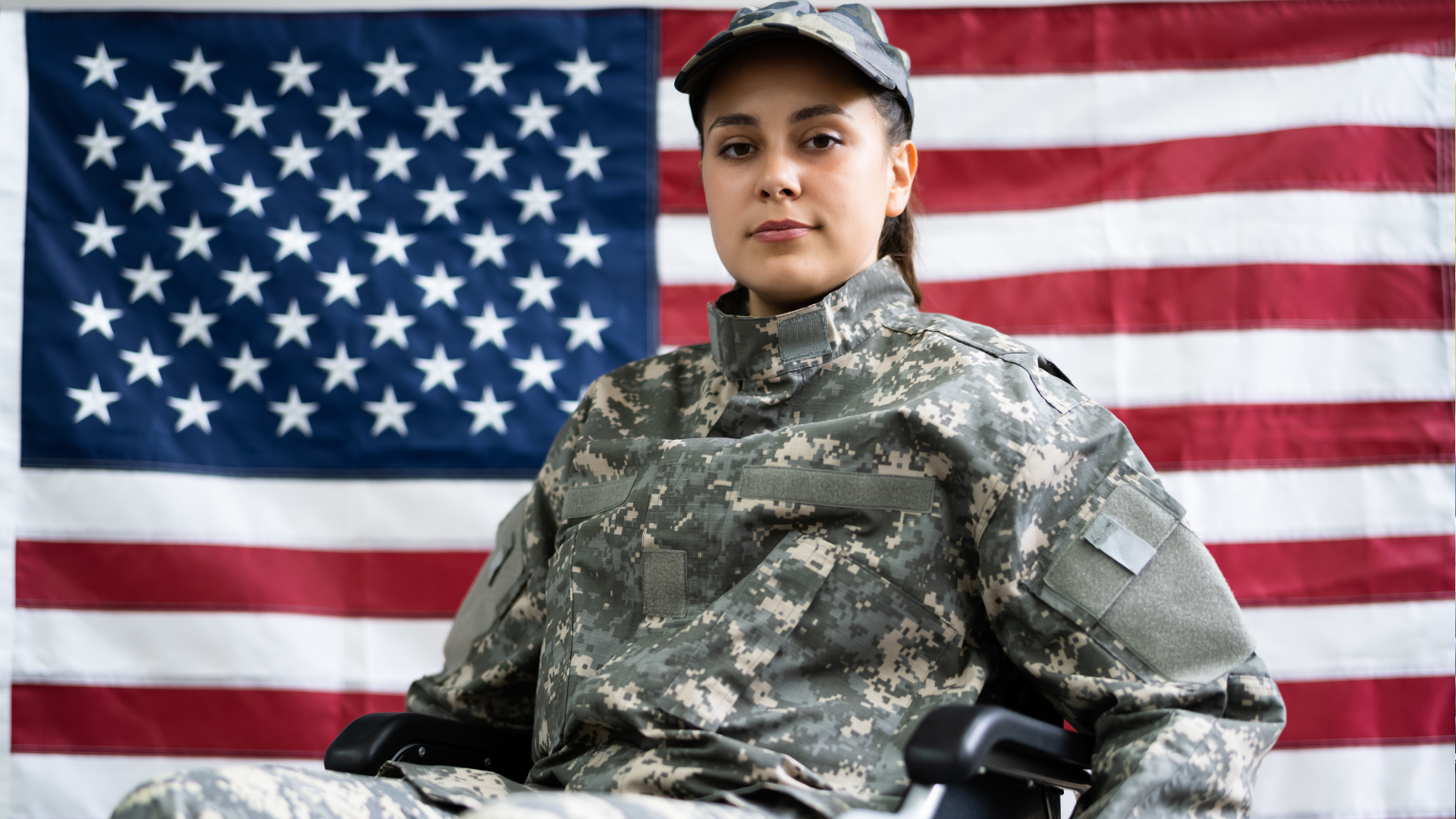 A woman in a wheelchair is sitting in front of an american flag.