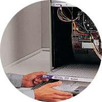 Technician connecting a cable to an open computer server rack inside a circular cutout image