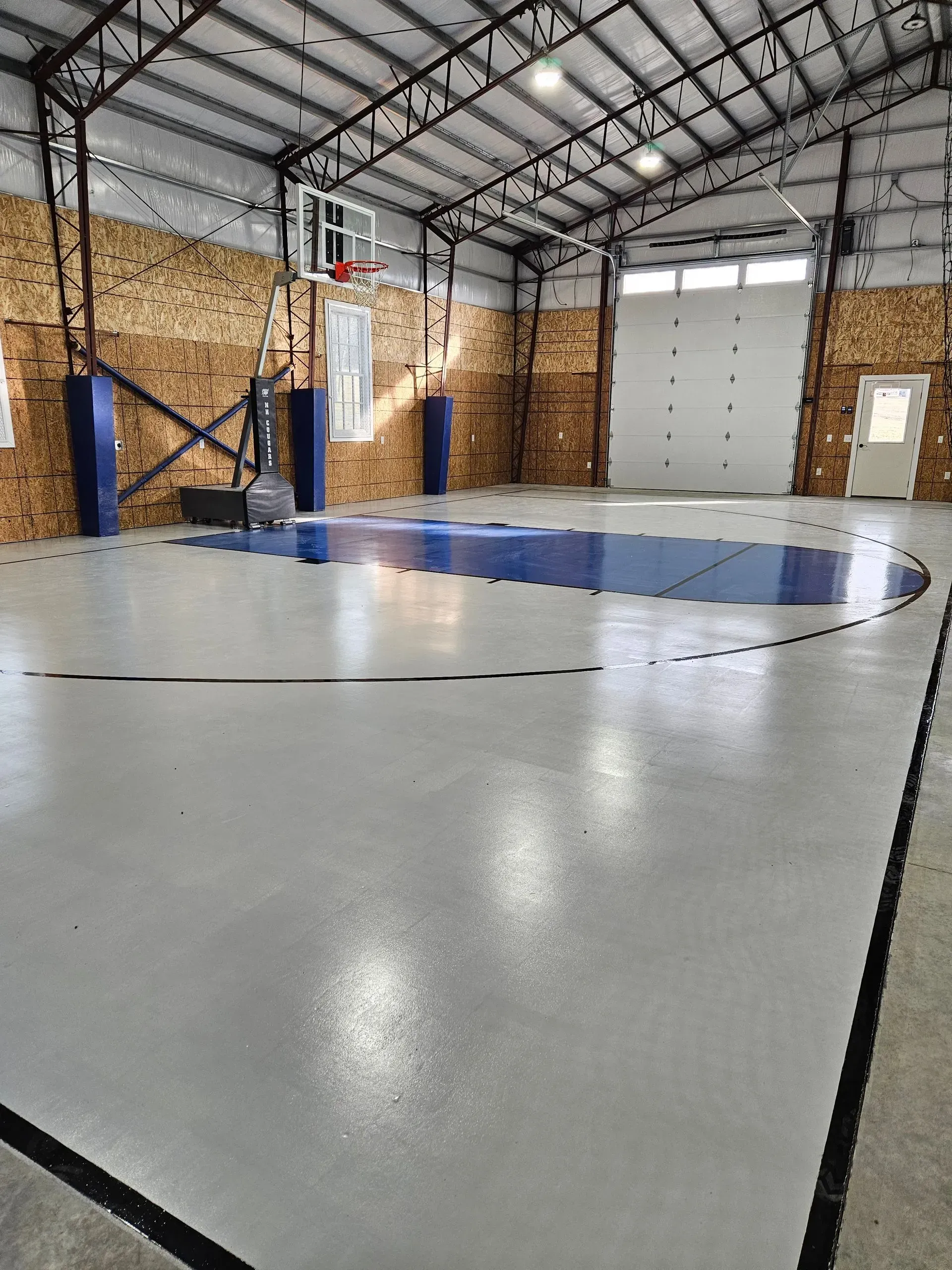 A basketball court inside of a building with a basketball hoop