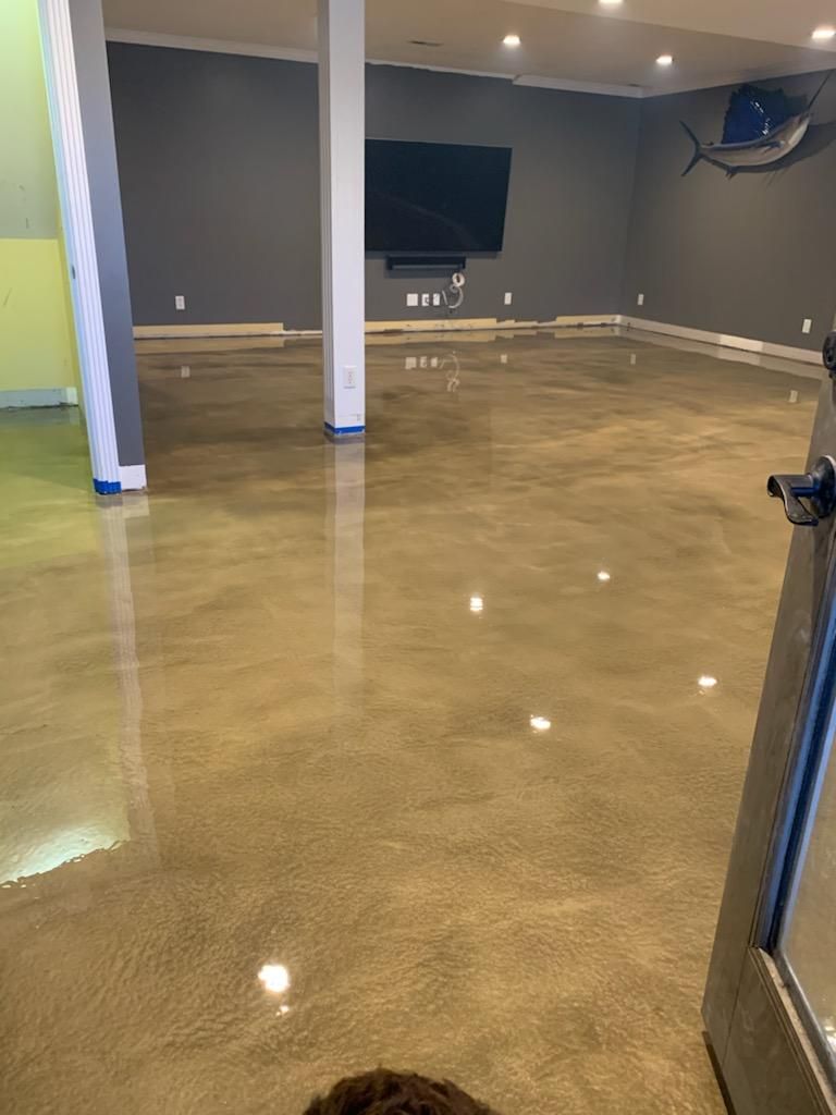 A basement with a shiny concrete floor and a flat screen tv.