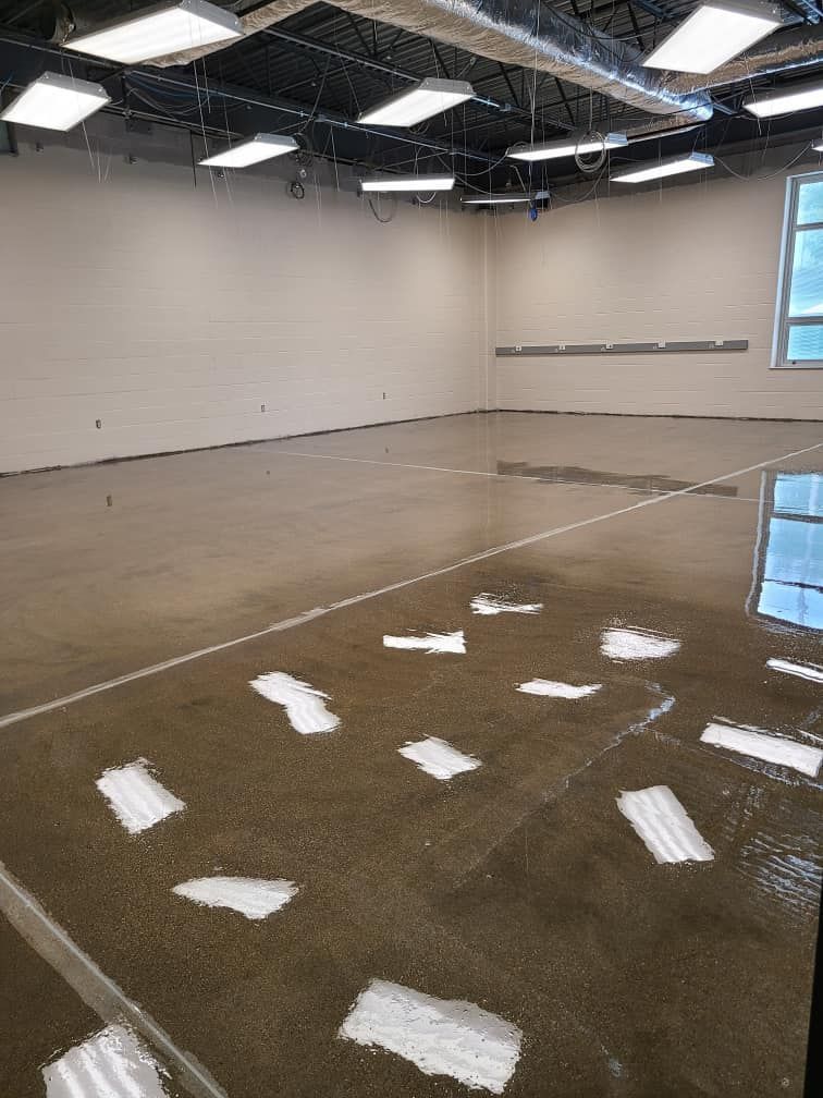 A large empty room with a concrete floor and a lot of lights on the ceiling.