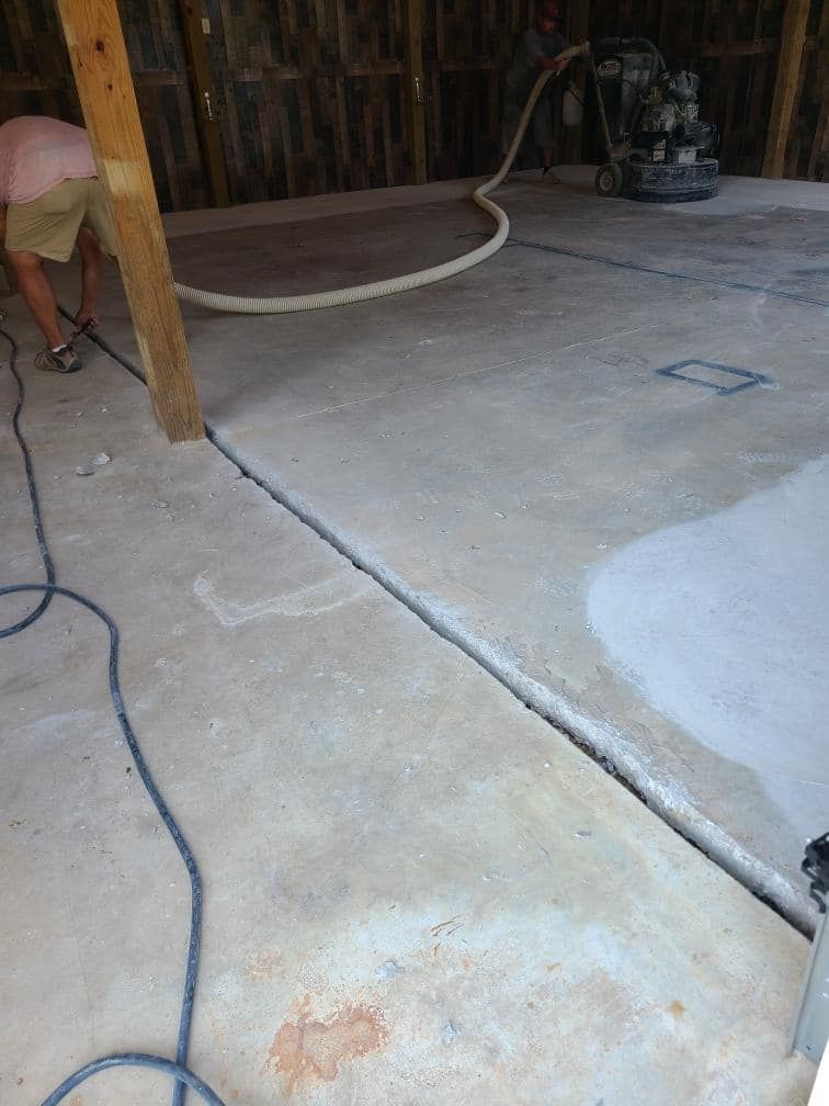 A man is working on a concrete floor in a garage.