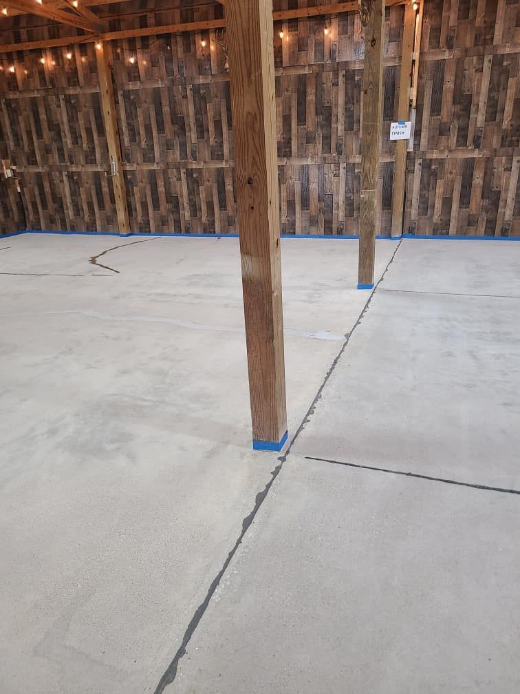 A large empty room with a concrete floor and wooden pillars.