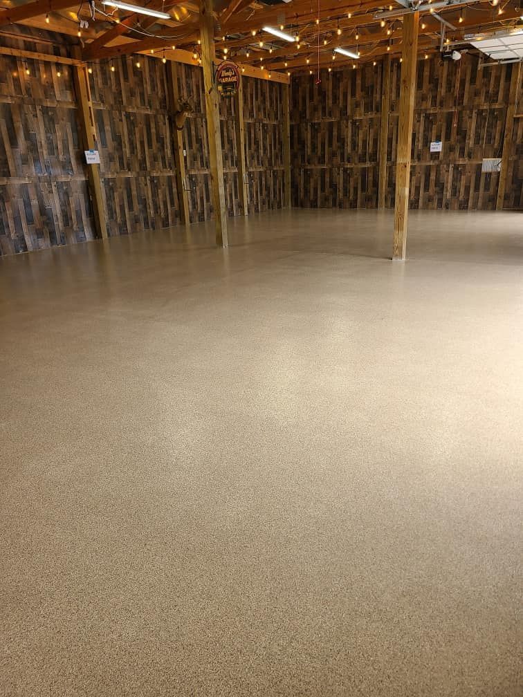 A large empty room with a concrete floor and wooden walls.