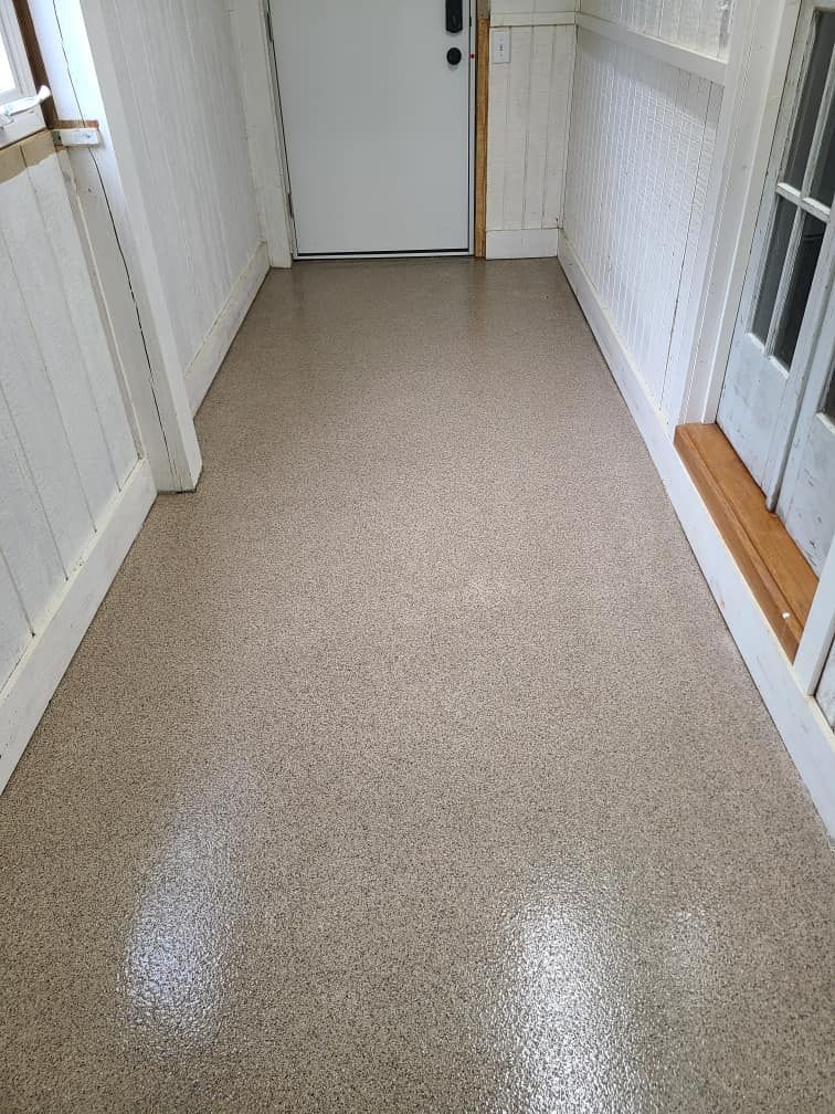 A hallway with a concrete floor and a white door.