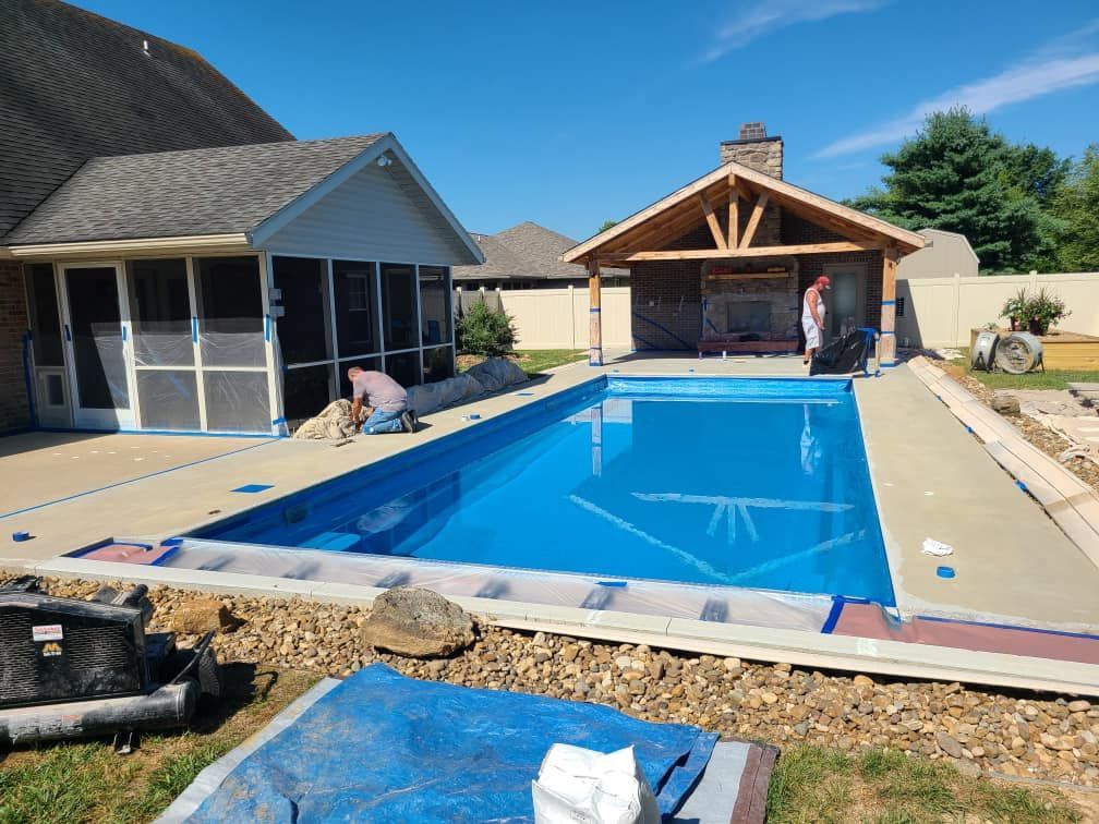 A large swimming pool is being built in the backyard of a house.