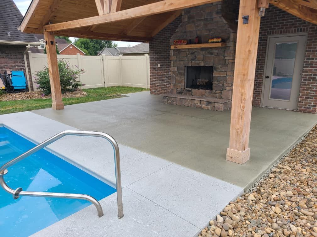 A patio with a fireplace and a swimming pool in the background.