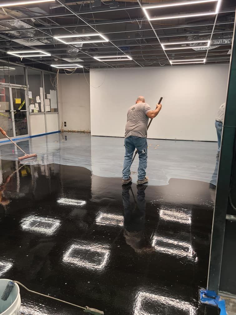 A man is standing on a black floor in a room.
