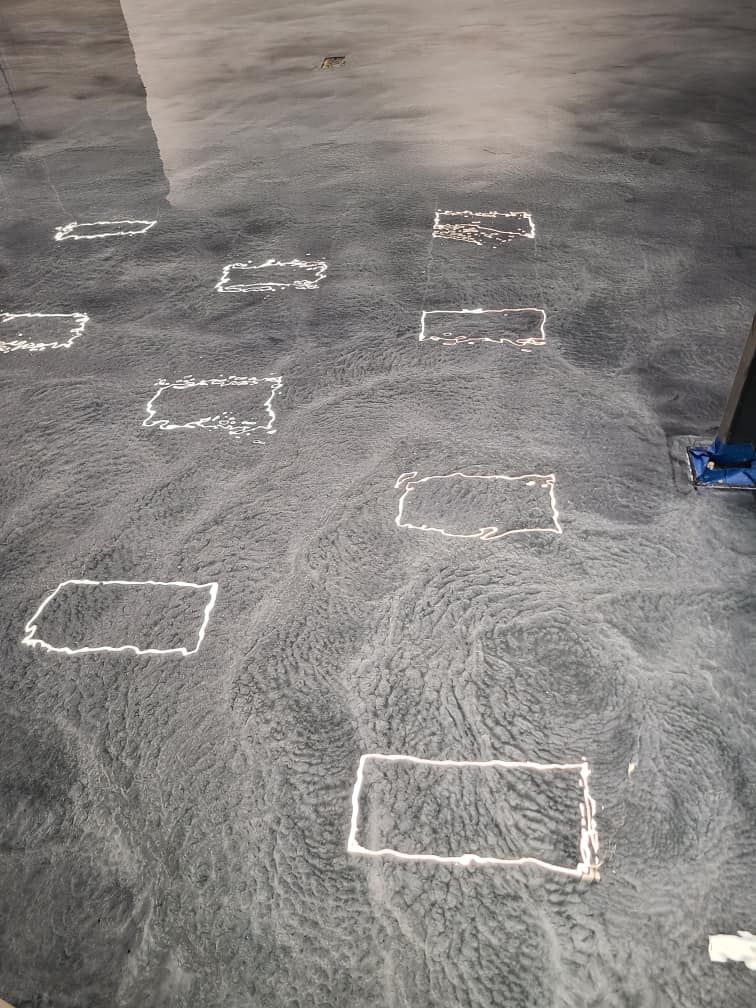 A gray concrete floor with white squares drawn on it.