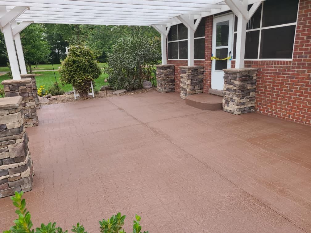A patio with a pergola over it and a brick house in the background.