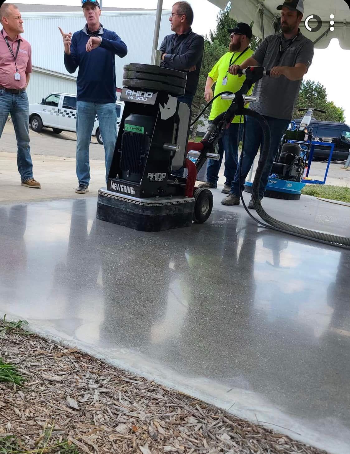 A group of men are standing around a machine on a concrete floor