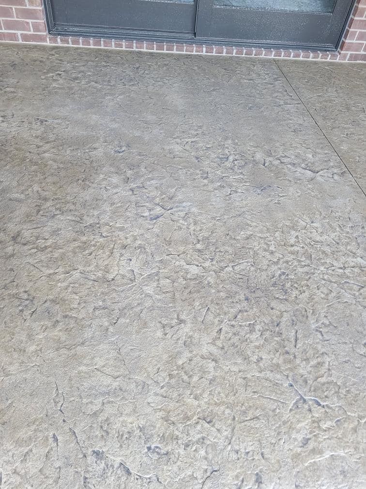 A concrete floor with a sliding glass door in the background.