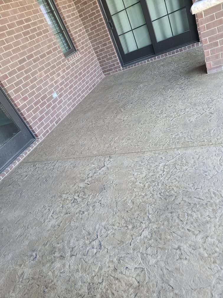 A patio with a brick wall and a concrete floor.