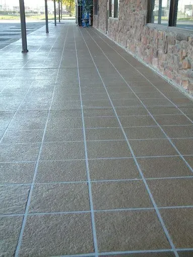 A tiled walkway leading to a building with a stone wall.