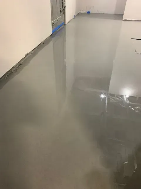 A gray epoxy floor in a room with a door.